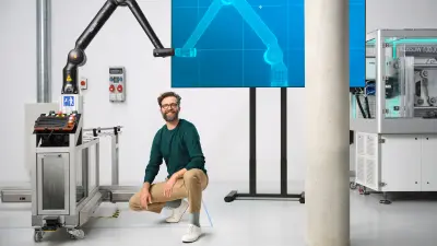 oi asociați se joacă la o masă de fotbal cu un robot de asistență Bosch Rexroth APAS.